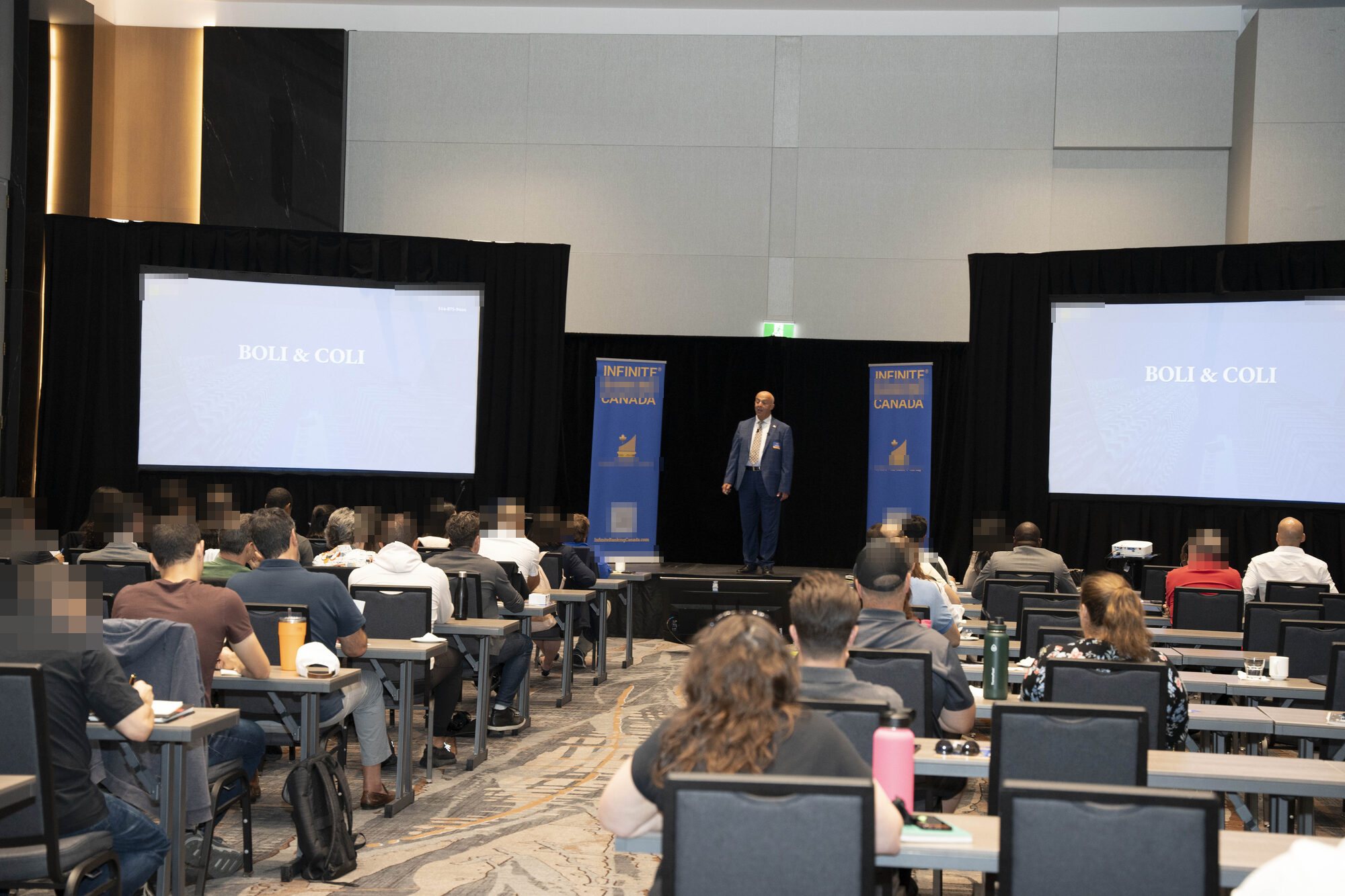 Jose Salloum on stage between two screens during a session on corporate-owned life insurance at a seminar in Laval